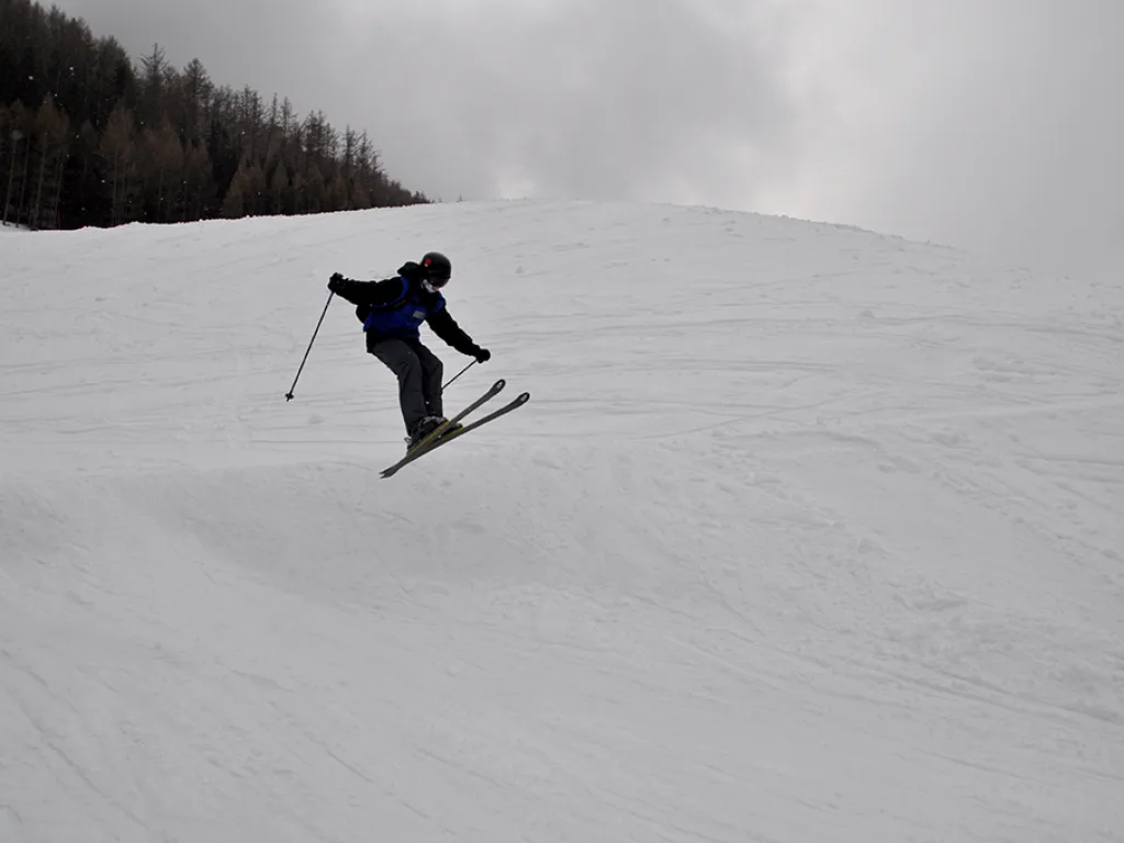 Skifahrer springt über eine Kuppe.